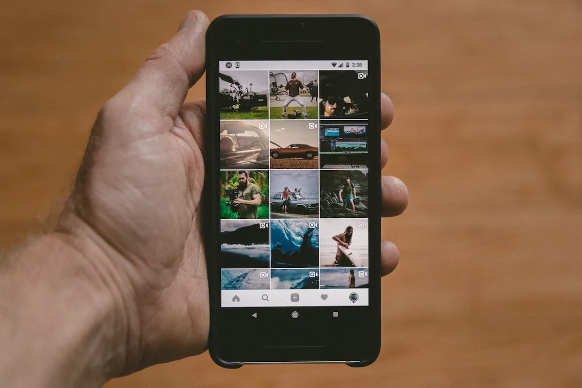 Una mano sujetando un móvil que muestra un muro de imágenes de Instagram