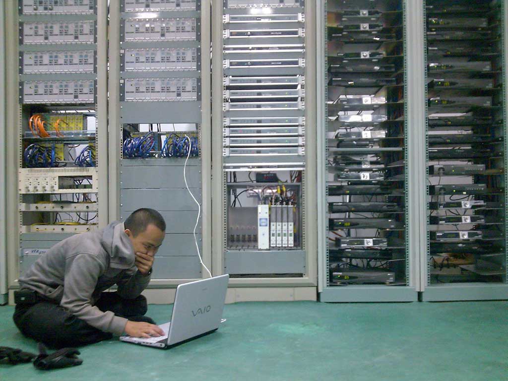Fotografía de un administrador de sistemas conectado a un servidor en un cuarto de servidores.