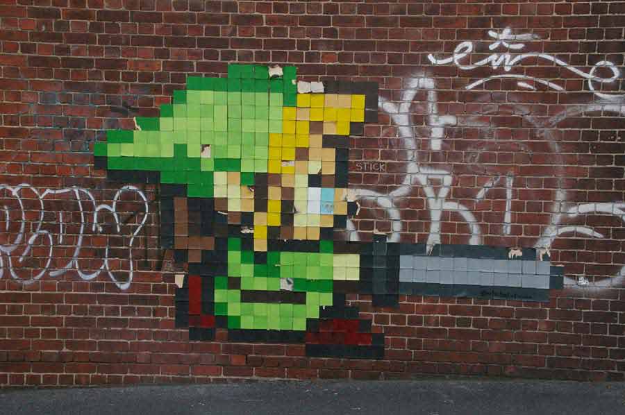 Fotografía de una pared de ladrillos cuadrados en la que los ladrillos representan un píxel del personaje del videojuego Zelda