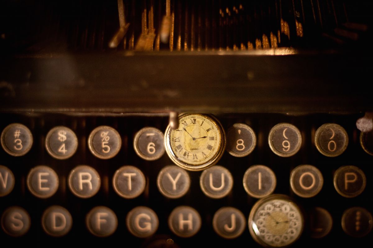 Imagen de un par de relojes de bolsillo sober una máquina de escribir antigua.